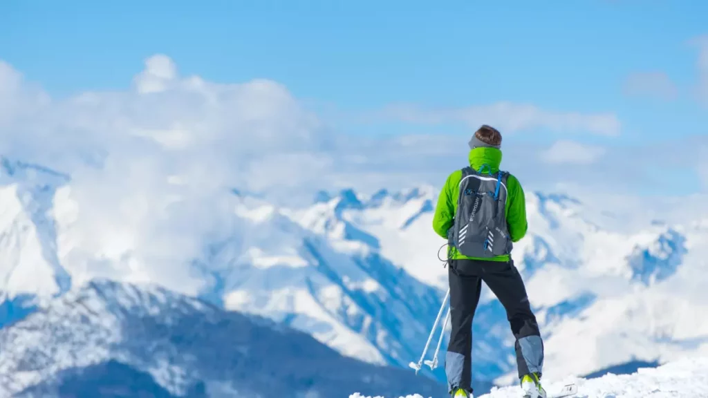 Man med grön jacka som åker med all mountain skidor