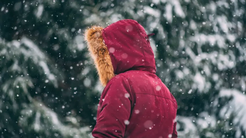 Kvinna med en röd vinterjacka ute i snön