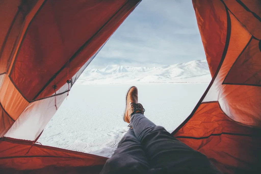 Man som ligger i ett campingtält på vintern